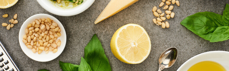 top view of pesto sauce raw ingredients and cooking utensils on grey surface, panoramic shot