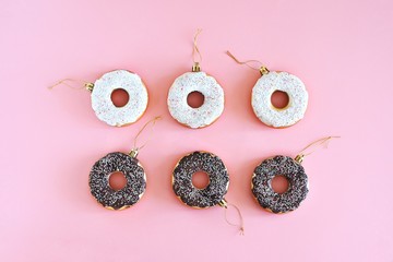 Christmas decoration donuts on a pastel pink background. New Year and Christmas creative concept. Top view, flat lay.