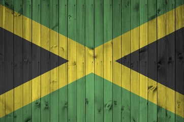 Jamaica flag depicted in bright paint colors on old wooden wall. Textured banner on rough background