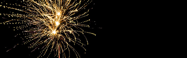 Obraz premium Panoramic shot of golden festive fireworks in night sky, isolated on black
