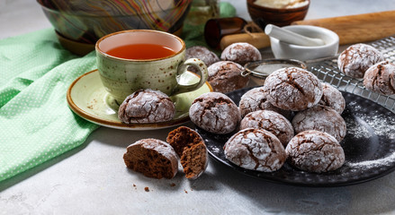 Cracked chocolate chip cookies in icing sugar. Chocolate christmas cookies on a white wooden table.