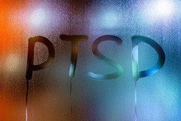 an abbreviation PTSD - post traumatic stress disorder - handwritten on wet glass of night window 