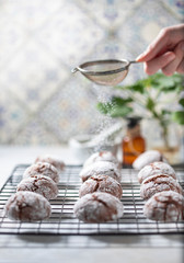 Cracked chocolate chip cookies in icing sugar. Chocolate christmas cookies on a white wooden table.
