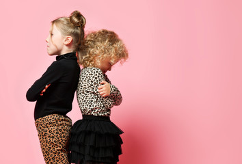 Two resentful kid girls best friends in leopard print clothes pants, sweater are standing with...