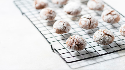Cracked chocolate chip cookies in icing sugar. Chocolate christmas cookies on a white wooden table.