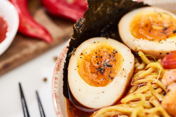 close up view of spicy ramen in bowl with eggs