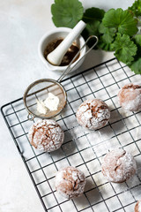 Cracked chocolate chip cookies in icing sugar. Chocolate christmas cookies on a white wooden table.