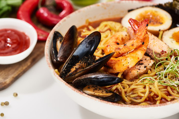 close up view of spicy seafood ramen with mussels and shrimps in bowl