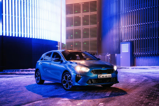 Kia Ceed car in night city against wall with neon color lights