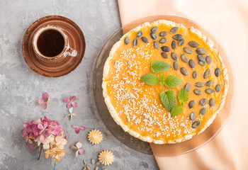 Traditional american sweet pumpkin pie decorated with mint, sesame and pumpkin seeds on a gray concrete background. top view, close up.