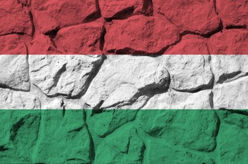 Hungary flag depicted in paint colors on old stone wall closeup. Textured banner on rock wall...