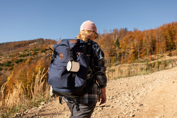 Hiker woman with backpack walking in the mountains in autumn scenery.