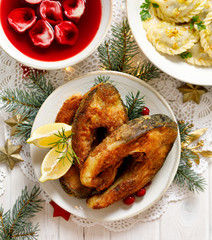 Christmas carp, Fried carp fish slices on a white plate on a holiday table, top view. Traditional christmas eve dish. Polish Christmas