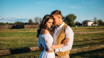 Boho style wedding. Beautiful and stylish couple bride and groom on a nature horse farm. Alone in the field green background.
