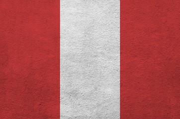 Peru flag depicted in bright paint colors on old relief plastering wall. Textured banner on rough...