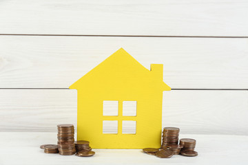 House model and coins on white wooden table