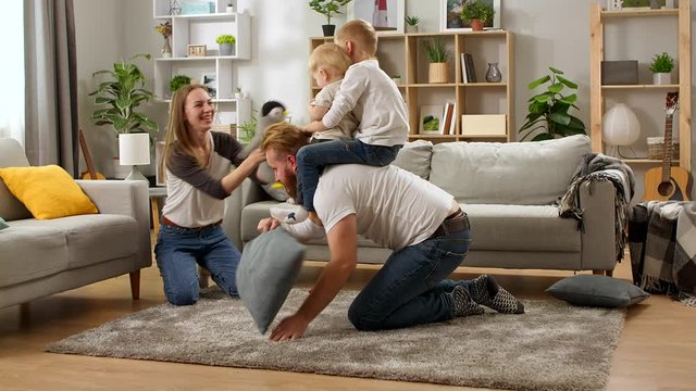 Young dad crawling on floor carrying cute small child sons on back