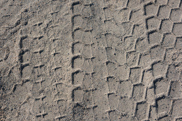 Honeycomb wheel prints on gray sandy ground closeup