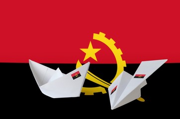 Angola flag depicted on paper origami airplane and boat. Handmade arts concept