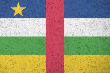 Central African Republic flag depicted in bright paint colors on old relief plastering wall....