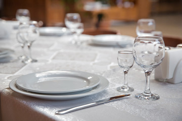Tables set for meal . fork, knife . empty glasses and plates on the table in the restaurant .