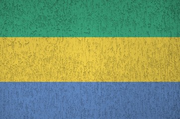 Gabon flag depicted in bright paint colors on old relief plastering wall. Textured banner on rough...