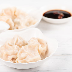Fresh, delicious boiled pork gyoza dumplings, jiaozi on white background with soy sauce and chopsticks, close up, lifestyle. Homemade design concept.
