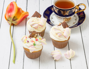 Cupcakes with cream, chocolate and tea.
