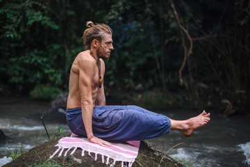 Yoga practice and meditation in nature. Man practicing near river