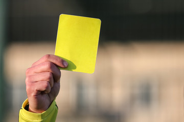 Football referee shows a yellow card.