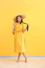 Fashionable young woman against color wall