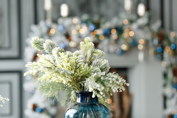 A Christmas tree branch, sprinkled with snow, stands in a decanter against the background of New...