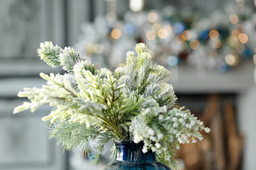 A Christmas tree branch, sprinkled with snow, stands in a decanter against the background of New...