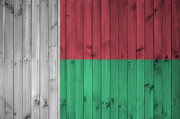 Madagascar flag depicted in bright paint colors on old wooden wall. Textured banner on rough...