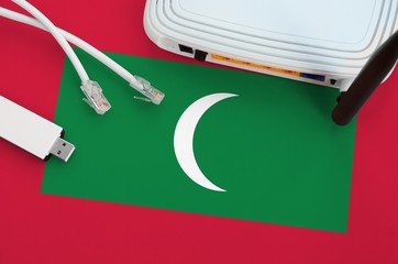 Maldives flag depicted on table with internet rj45 cable, wireless usb wifi adapter and router....
