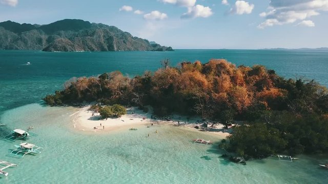 flying towards a very small filipino island with many Banca boats floating around it.