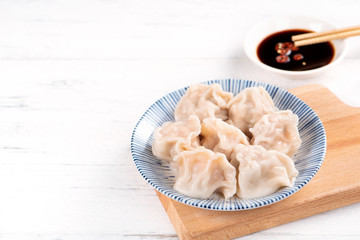 Fresh, delicious boiled pork gyoza dumplings, jiaozi on white background with soy sauce and chopsticks, close up, lifestyle. Homemade design concept.