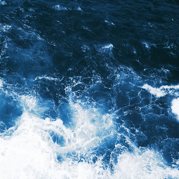 Top view on blue ocean waves and foam.