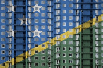 Solomon Islands flag depicted in paint colors on multi-storey residental building under...