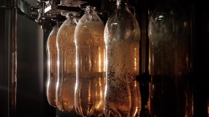 Fresh carbonated beverages production using modern equipment. gold color organic drinks fill a lot of bottles and move around the production line. Automation of the food industry close-up.
