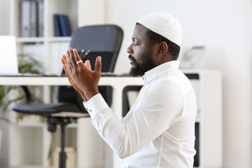 African-American Muslim man praying in office