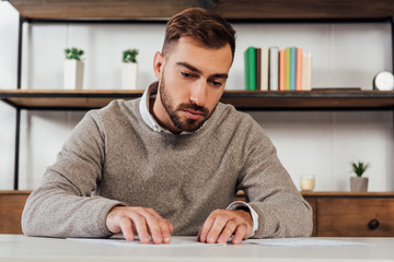 Visually impaired man reading braille font at table