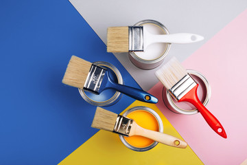 Four open cans with brushes on them on bright symmetry background. Yellow, white, pink, blue colors of paint. Renovation concept. - 307626808