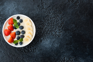 Delicious, healthy and balanced Breakfast of oatmeal with berries and fruit in a plate on the left...