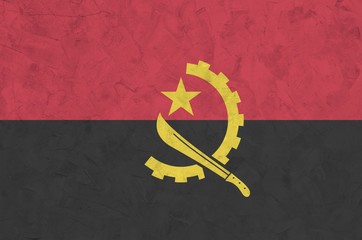 Angola flag depicted in bright paint colors on old relief plastering wall. Textured banner on rough...