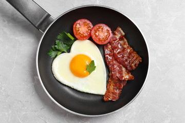 Tasty breakfast with heart shaped fried egg on grey table, top view