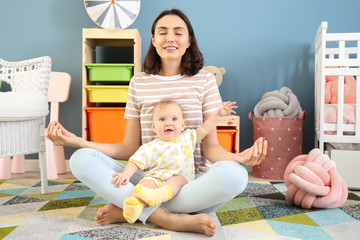 Young mother with little baby meditating at home