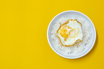 cooked rice with fried egg on bowl on yellow background