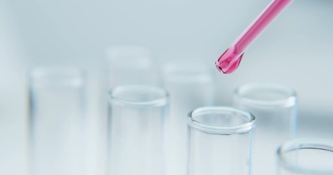 Close-up shot with hitting laboratory equipment. Red liquid falling pipette in glass test tube.