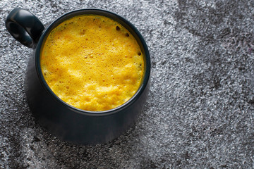 Turmeric latte with cinnamon. Coffe with golden milk. Hot healthy drink. Dark concrete background. Empty space. Top view.